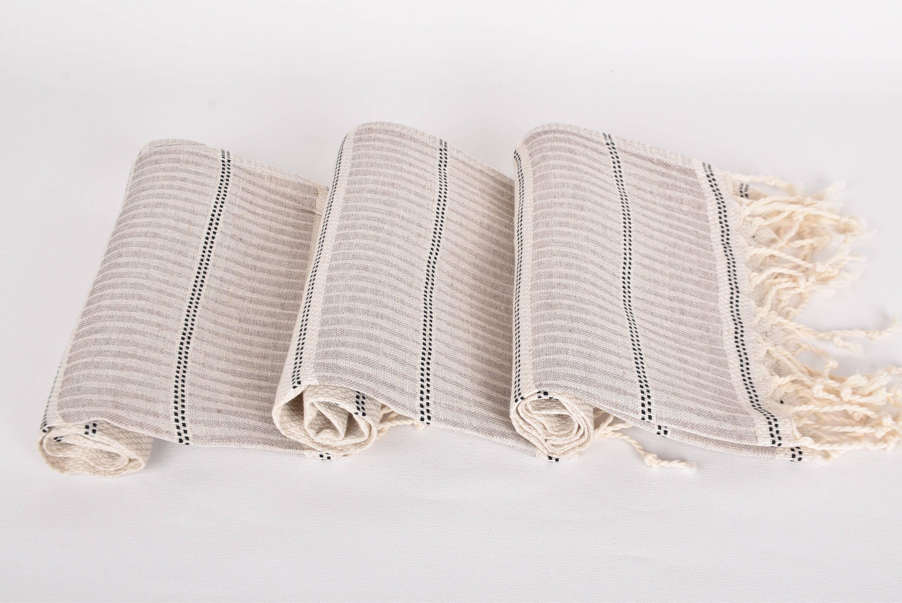 Three folded towels with tassels on a light gray background