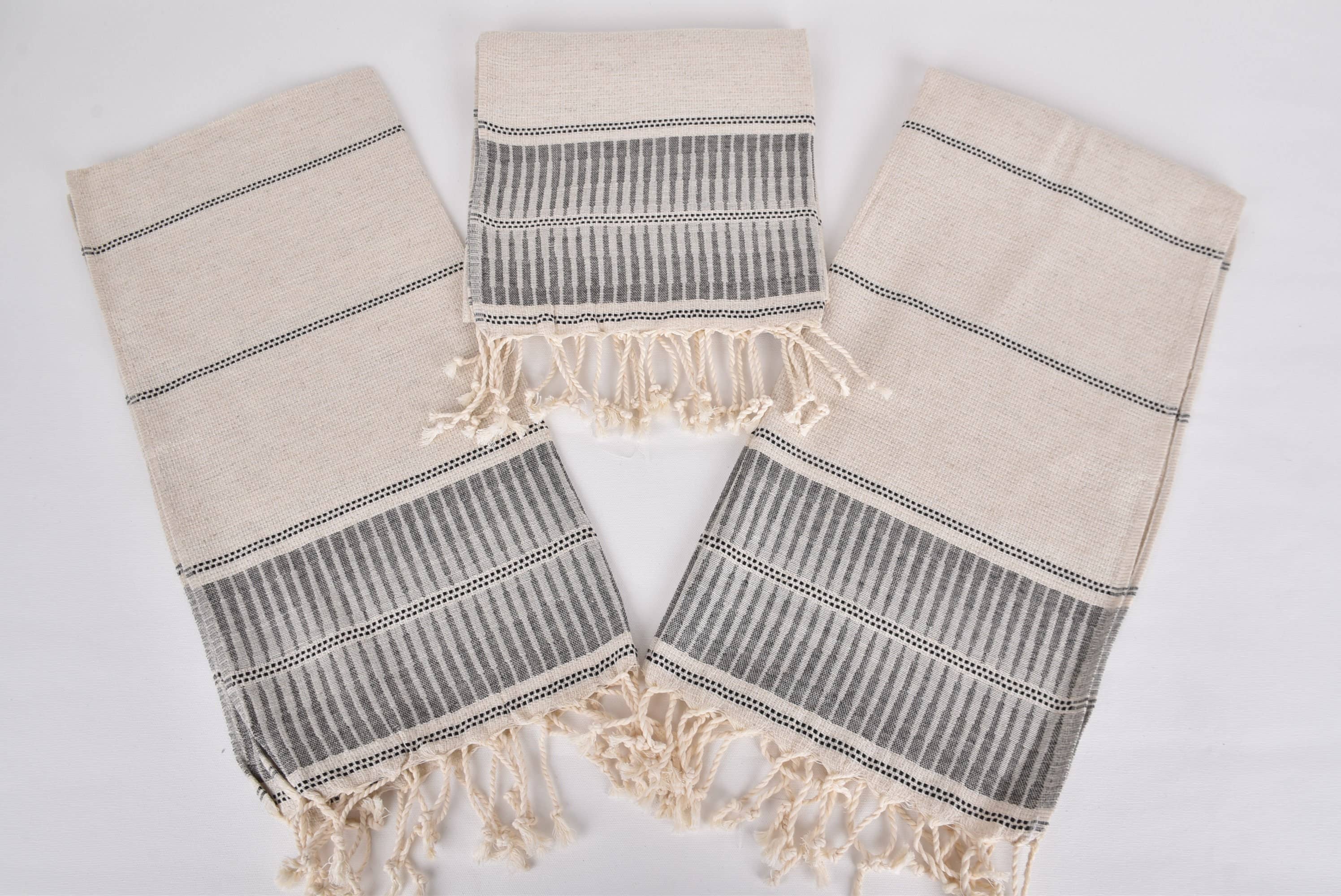 Three beige and gray patterned towels with fringes on a white background