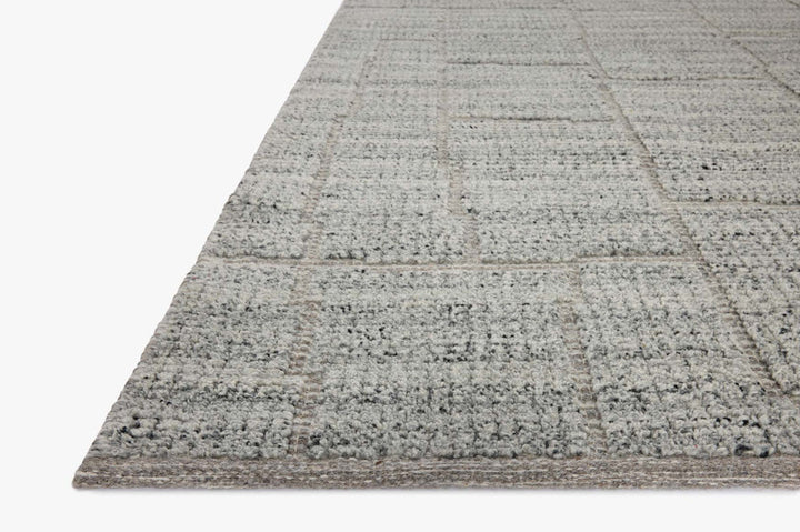Gray textured area rug corner close up with subtle grid pattern and low pile weave