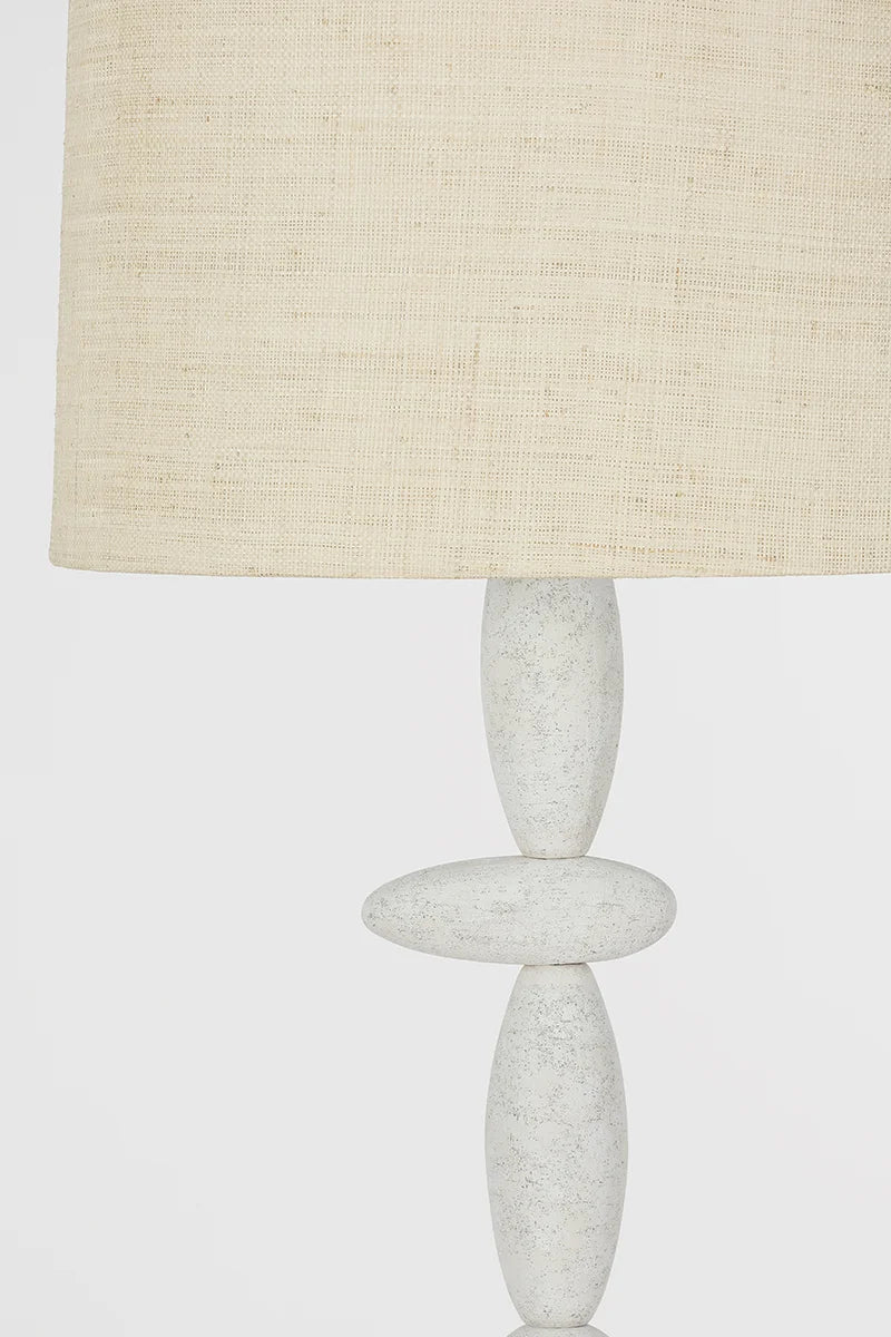 A close-up of the Cullen Floor Lamp with a beige textured fabric lampshade and a white, sculptural base featuring stacked oval shapes that evoke a totemic silhouette.