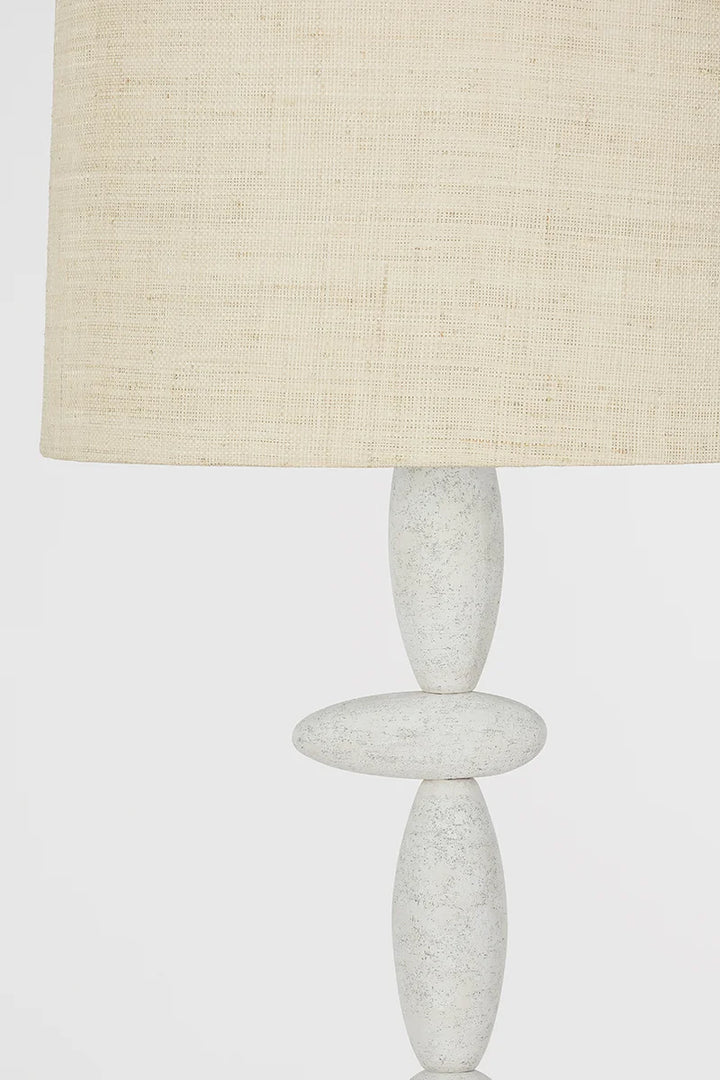 A close-up of the Cullen Floor Lamp with a beige textured fabric lampshade and a white, sculptural base featuring stacked oval shapes that evoke a totemic silhouette.