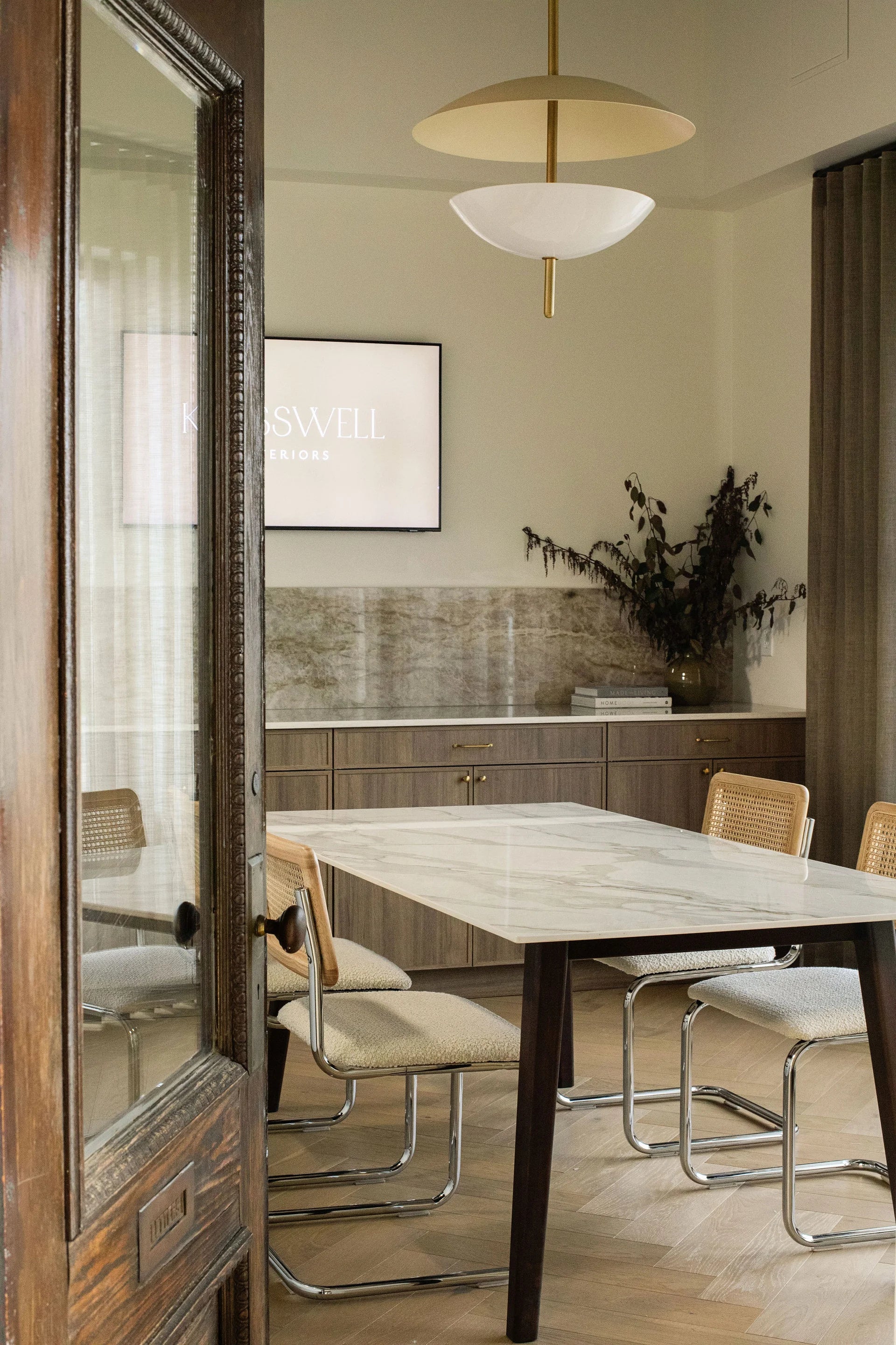 Modern dining room with marble table and chairs, wooden floor, and decorative elements.