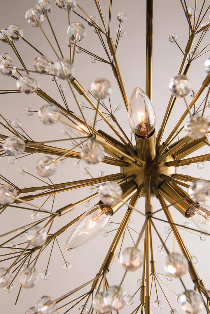 Close-up of gold starburst chandelier with crystal bead accents and candle-style bulbs, modern statement lighting fixture