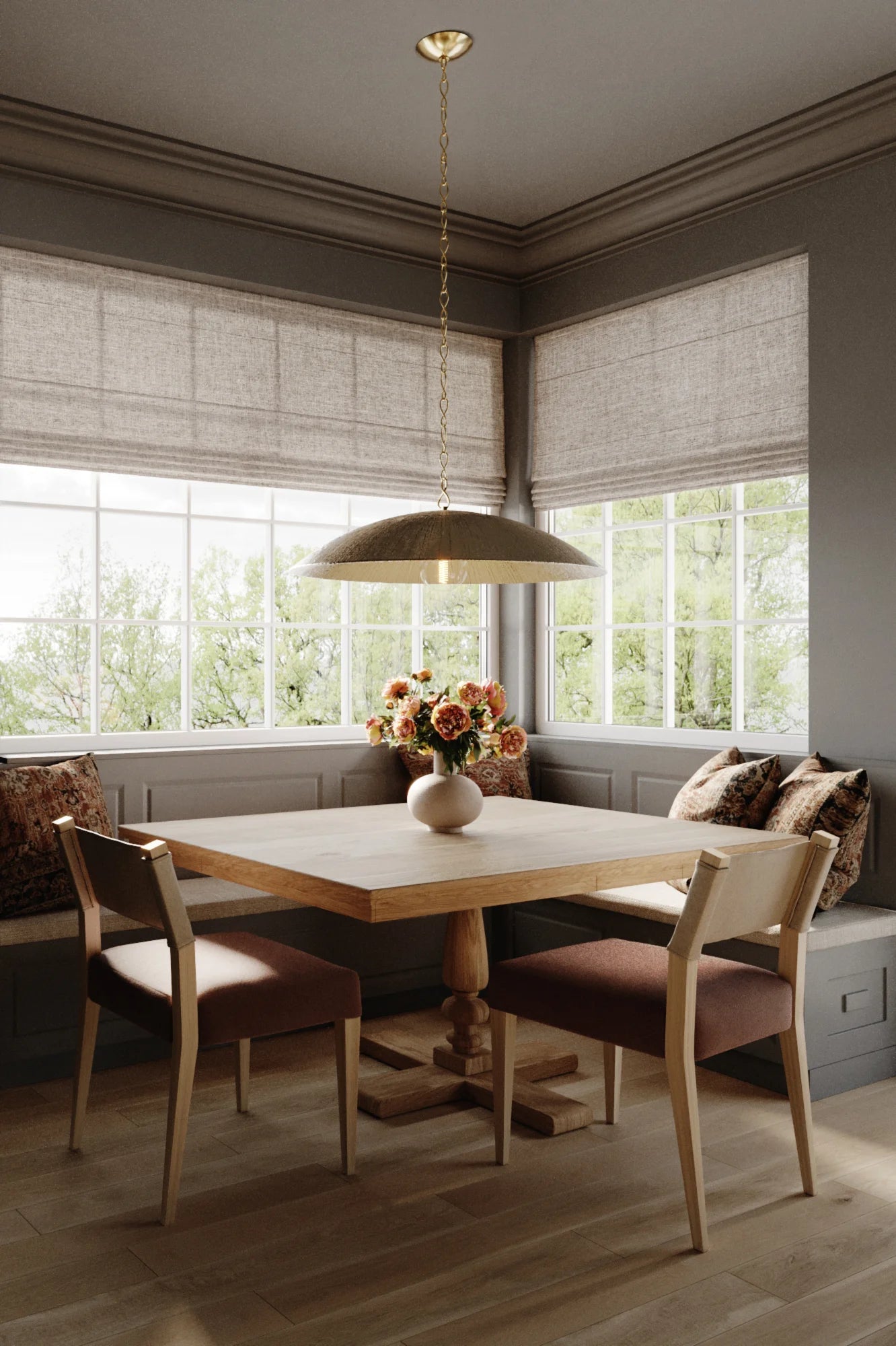A modern pendant ceiling light with a sculptural dome shape, in a warm silver leaf finish, hanging over a wooden table with four chairs in a room with window treatments and decor.