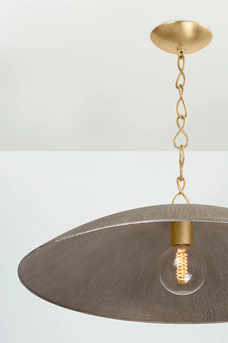 Close-up of dome pendant light with antique brass chain, textured metal shade, and glowing exposed filament bulb on light background