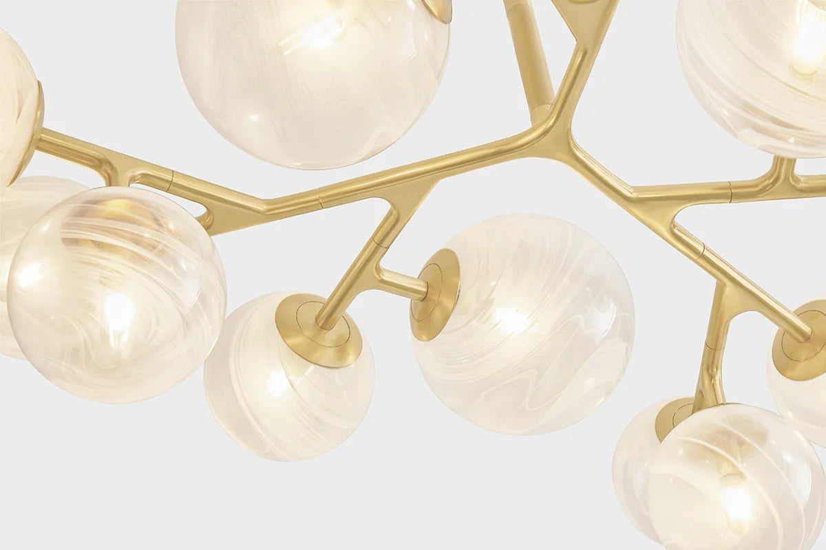 Close-up of modern branching chandelier in brass with frosted glass globe shades and warm ambient lighting