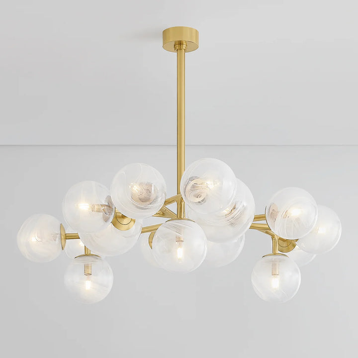 Modern brass chandelier with clear glass globe shades and warm bulbs, contemporary ceiling light fixture on a white background