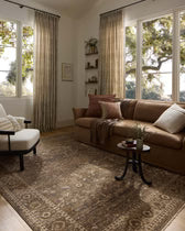Living room with brown sofa, armchair, and coffee table near large windows.