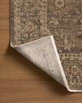 Close-up of a brown and beige patterned rug on a wooden floor.