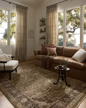 Living room with brown sofa, patterned rug, and large windows.