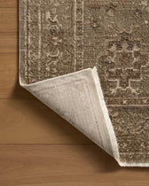 Close-up of a brown and beige patterned rug on a wooden floor.