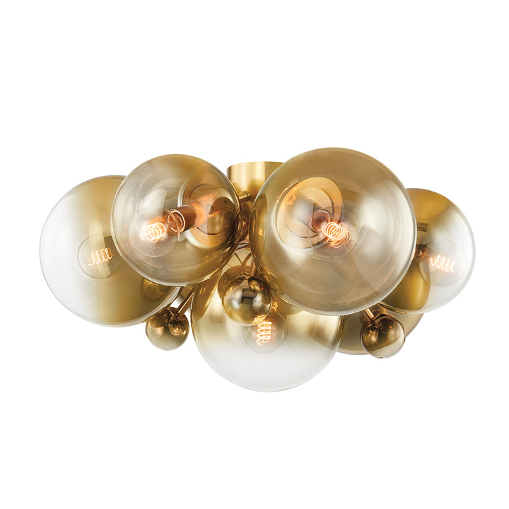 Clustered ombre glass globe ceiling light fixture in a room with wood accent wall and a bed with beige bedding.