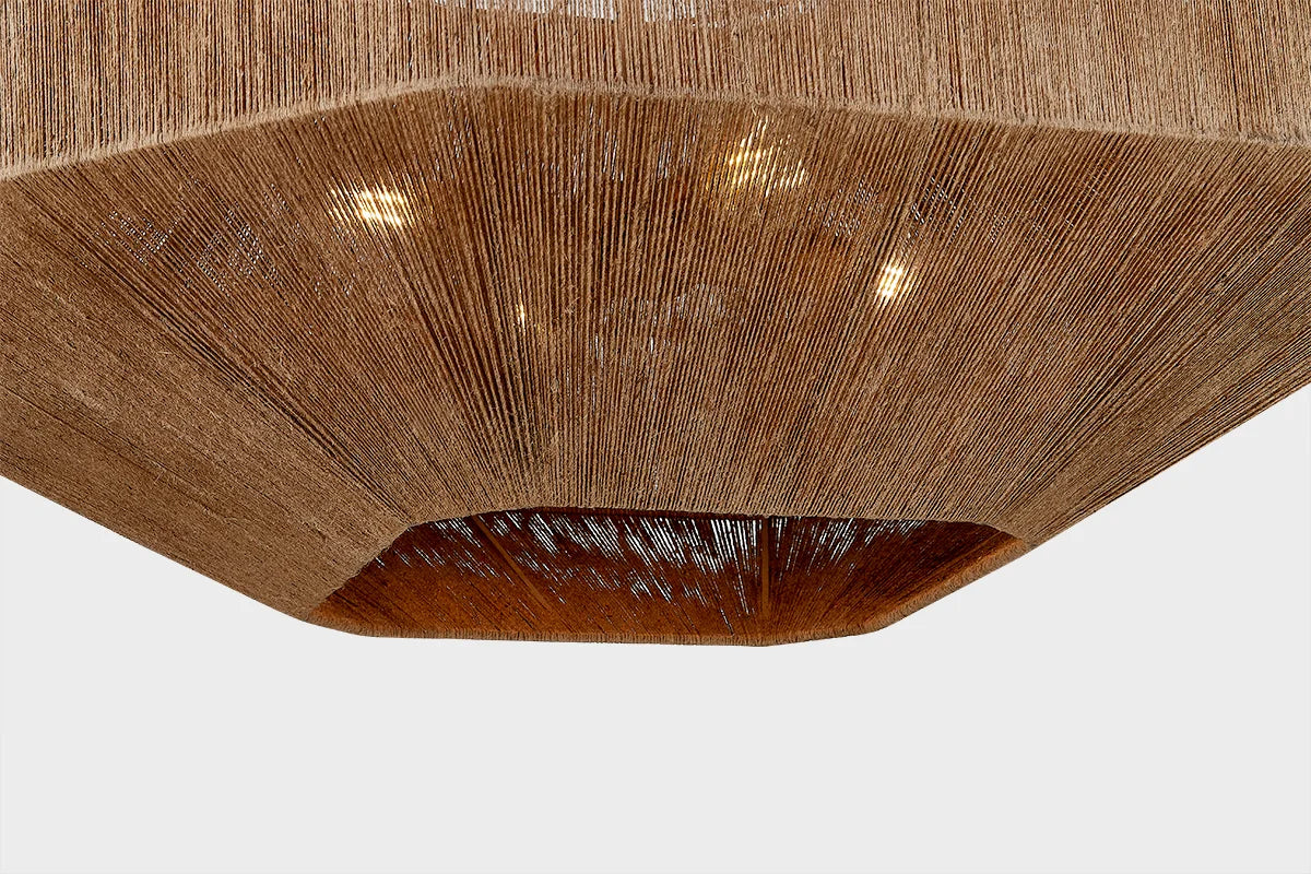 Underside view of woven natural fiber ceiling light with warm glow and textured rattan-style shade
