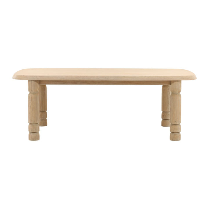 A rectangular dining table with a light natural wood finish and visible wood grain patterns. The table has a plain top and decorative legs.
