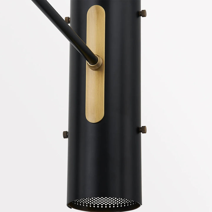 Close-up of black metal wall sconce shade with brass accent plate and adjustable arm hardware, modern lighting fixture detail