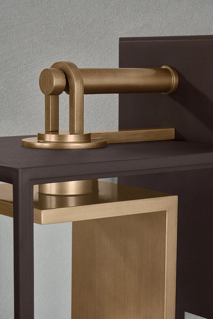 Close-up of outdoor wall lantern showing brass hinge hardware, dark metal frame, and textured panel detail