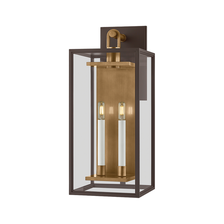 Modern outdoor wall lantern sconce with dark bronze rectangular frame, clear glass panels, and brass backplate with two candle-style lights