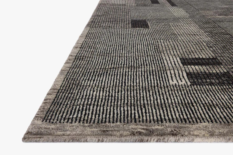 Corner close-up of modern gray area rug with black line grid pattern and low pile texture on white background