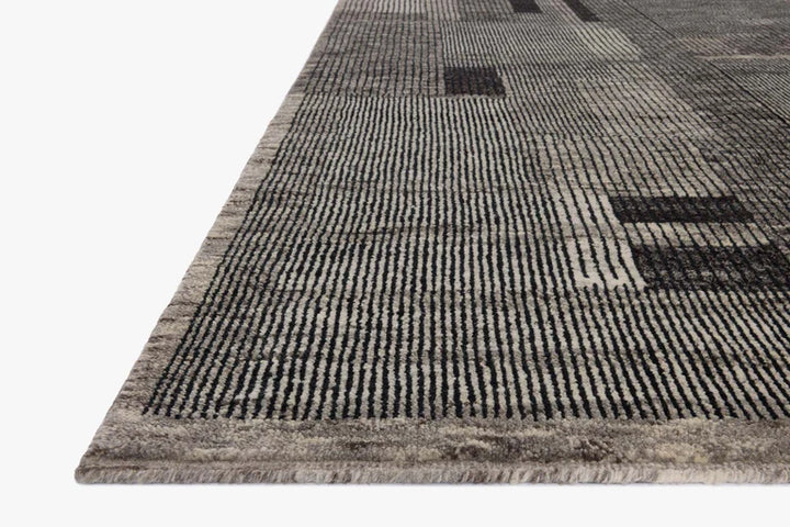Corner close-up of modern gray area rug with black line grid pattern and low pile texture on white background