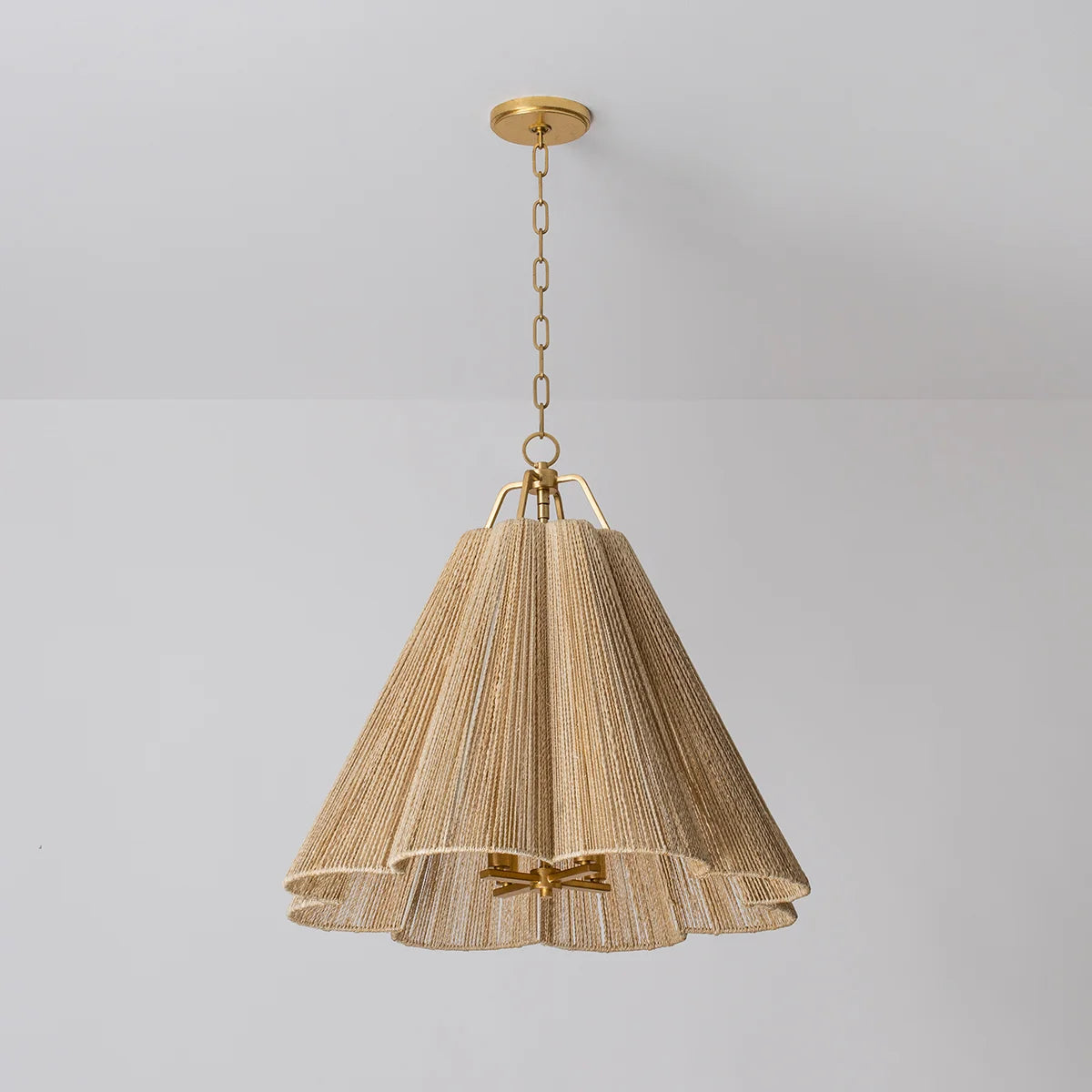 A ceiling-mounted light fixture with a beige, scalloped, bell-shaped shade and metalwork. The light has a warm tone, and the material appears to be woven or textured.