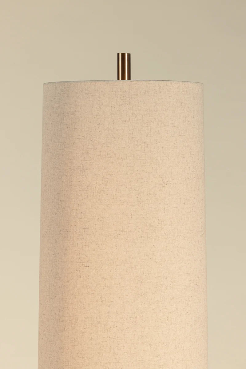 Modern brass floor lamp with woven rattan wrap and square metal base on wood floor