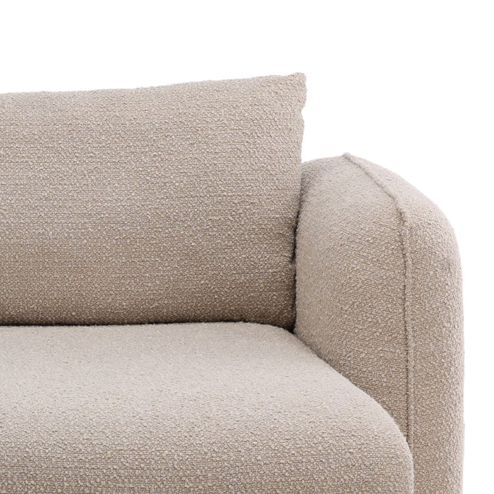 Close-up of beige boucle sectional sofa showing corner seat, back cushion, and rounded armrest texture detail