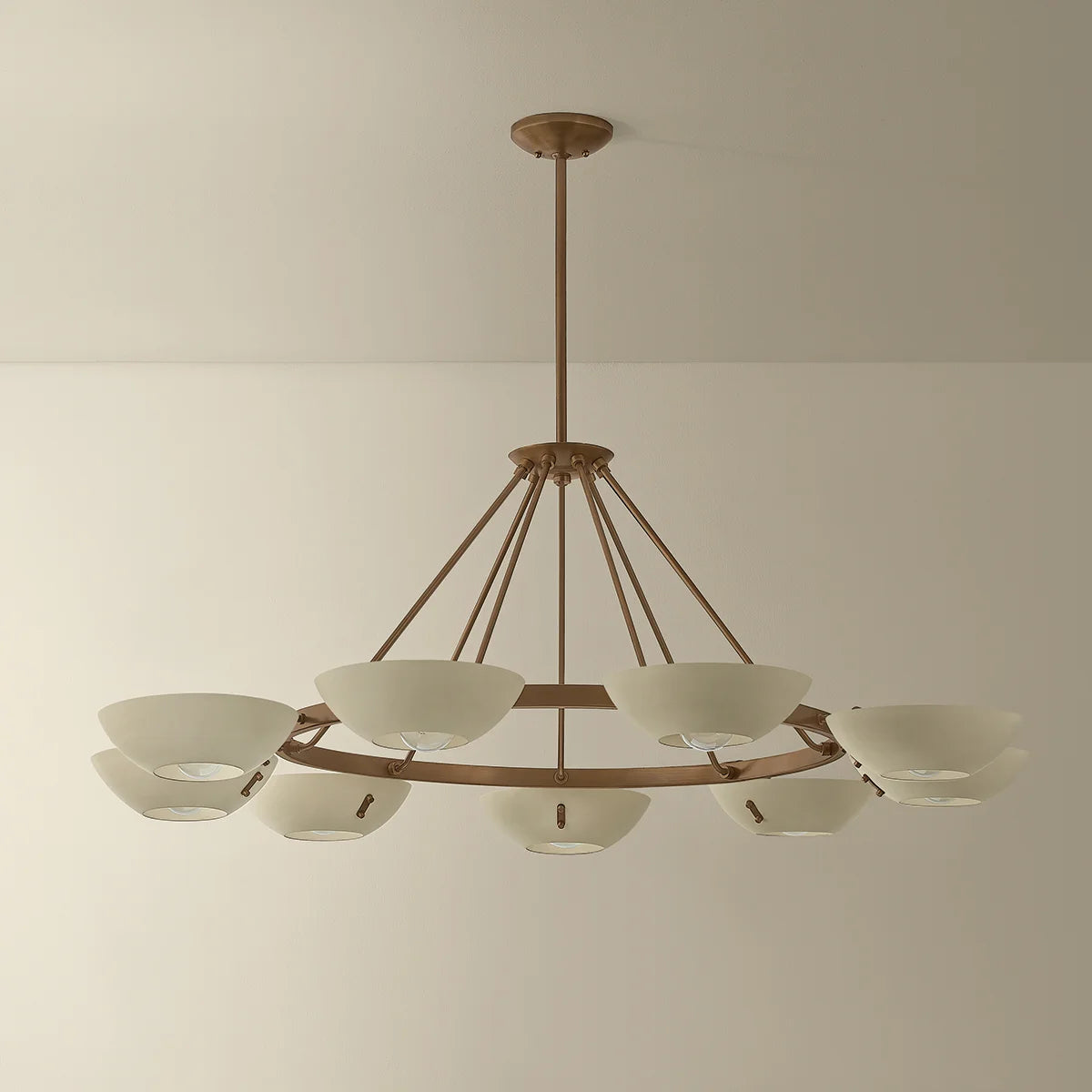 Large brass chandelier with white bowl shades and a circular frame suspended from the ceiling