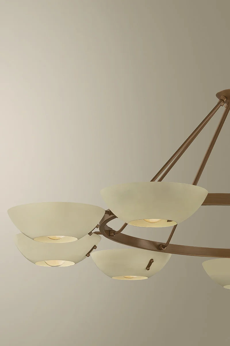 Close-up of a brass chandelier with frosted white bowl shades and circular ring frame