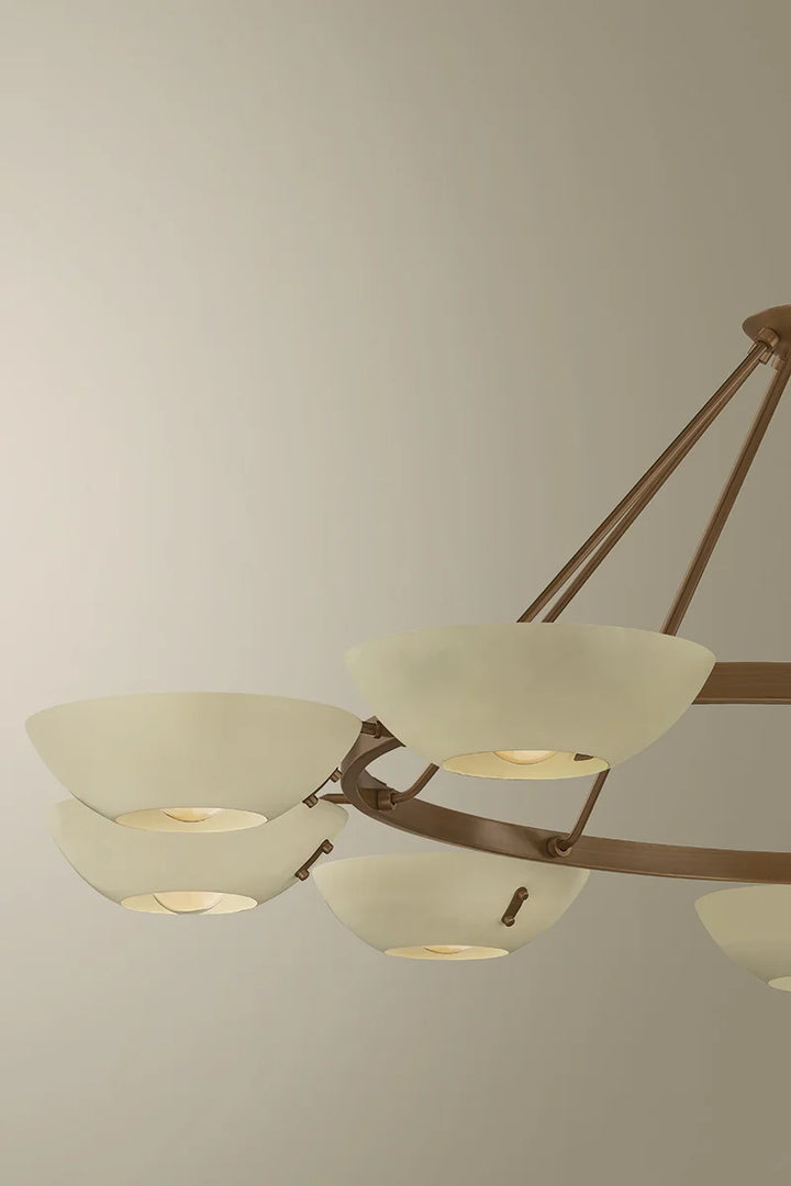 Close-up of a brass chandelier with frosted white bowl shades and circular ring frame