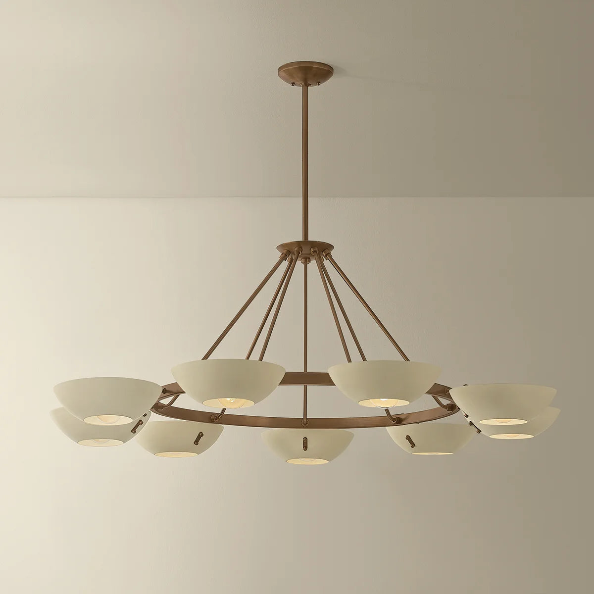 Large brass ring chandelier with white bowl shades and warm ambient lighting suspended from the ceiling