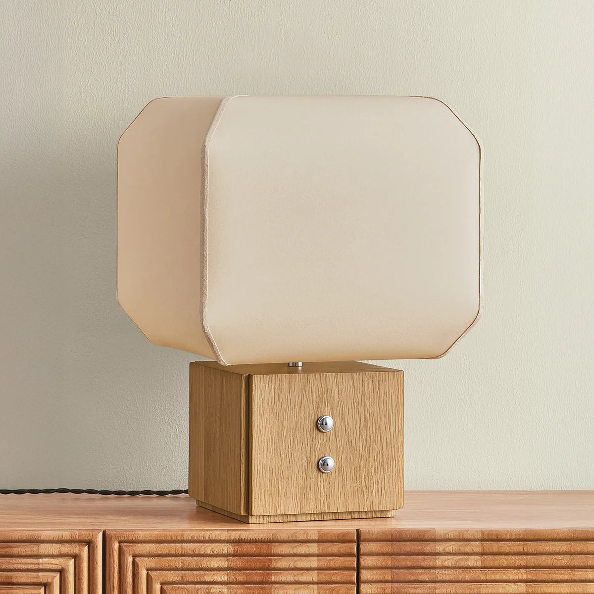 Table lamp with wooden base and beige fabric shade on a wooden surface.