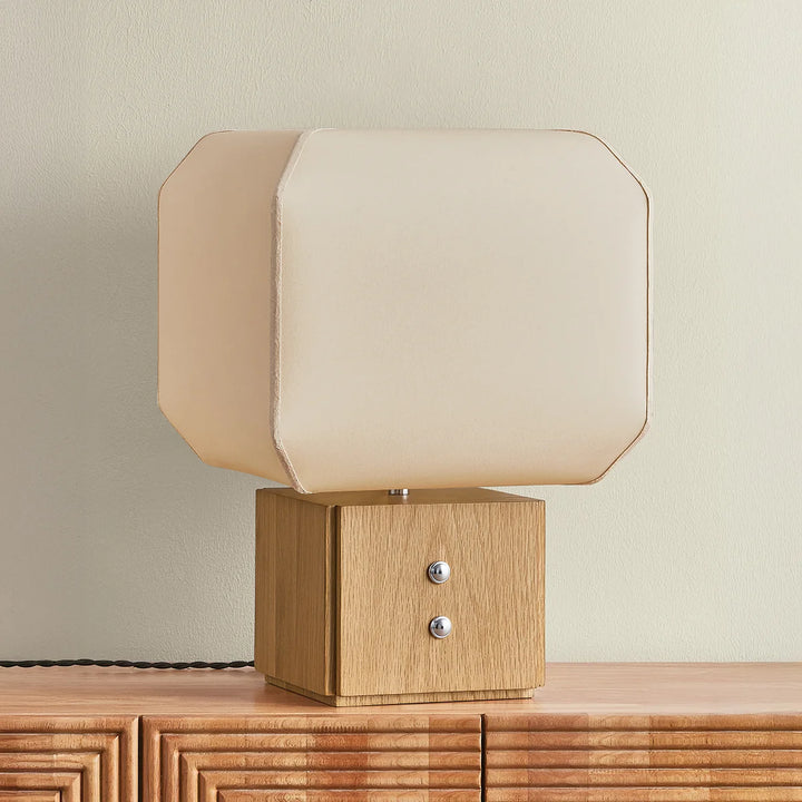 Table lamp with wooden base and beige fabric shade on a wooden surface.