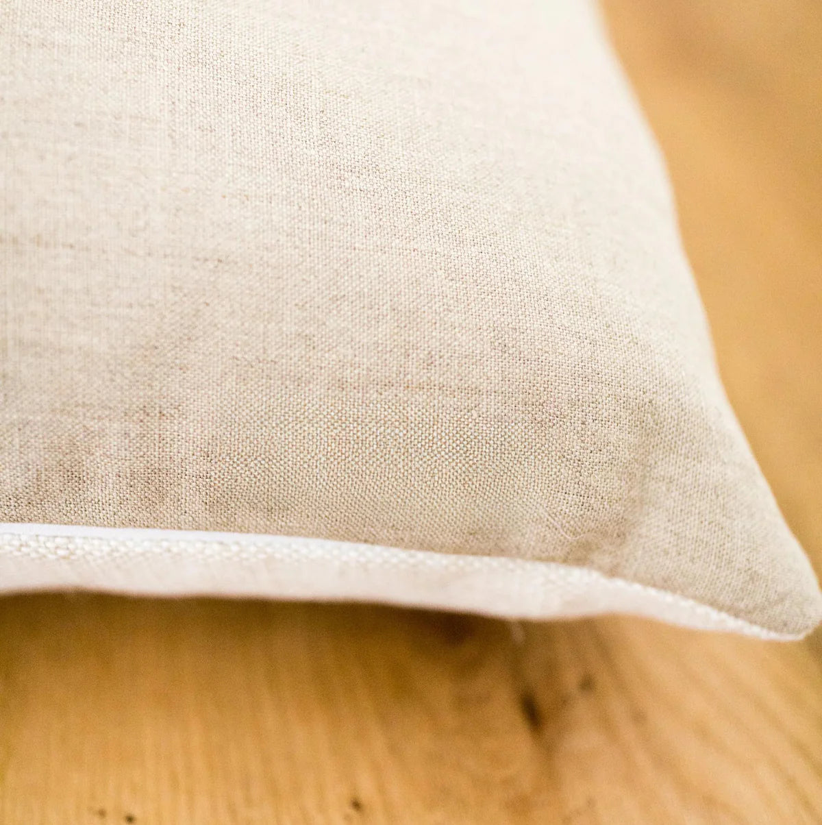 Close-up of a beige fabric pillow on a wooden surface