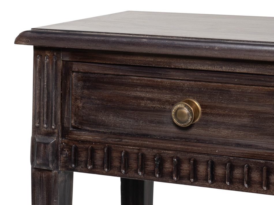 Close-up of dark wood console table drawer with brass knob and carved trim detailing on the apron and corner leg