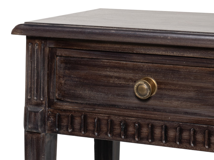 Close-up of dark wood console table drawer with brass knob and carved trim detailing on the apron and corner leg