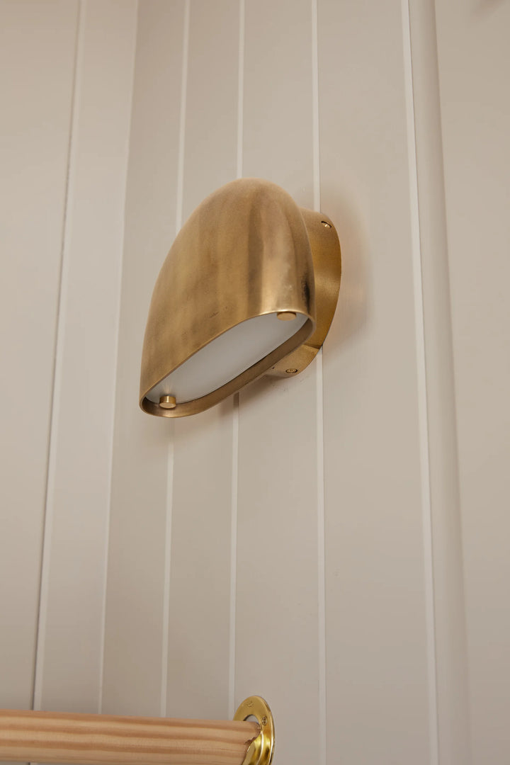 Gold wall-mounted light fixture on a white paneled wall