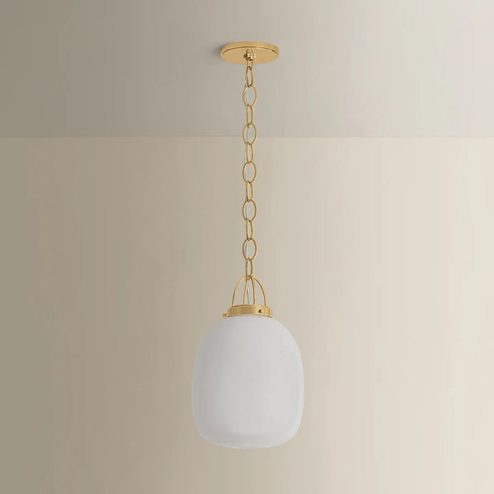 Pendant light with white glass shade and gold chain against a beige wall