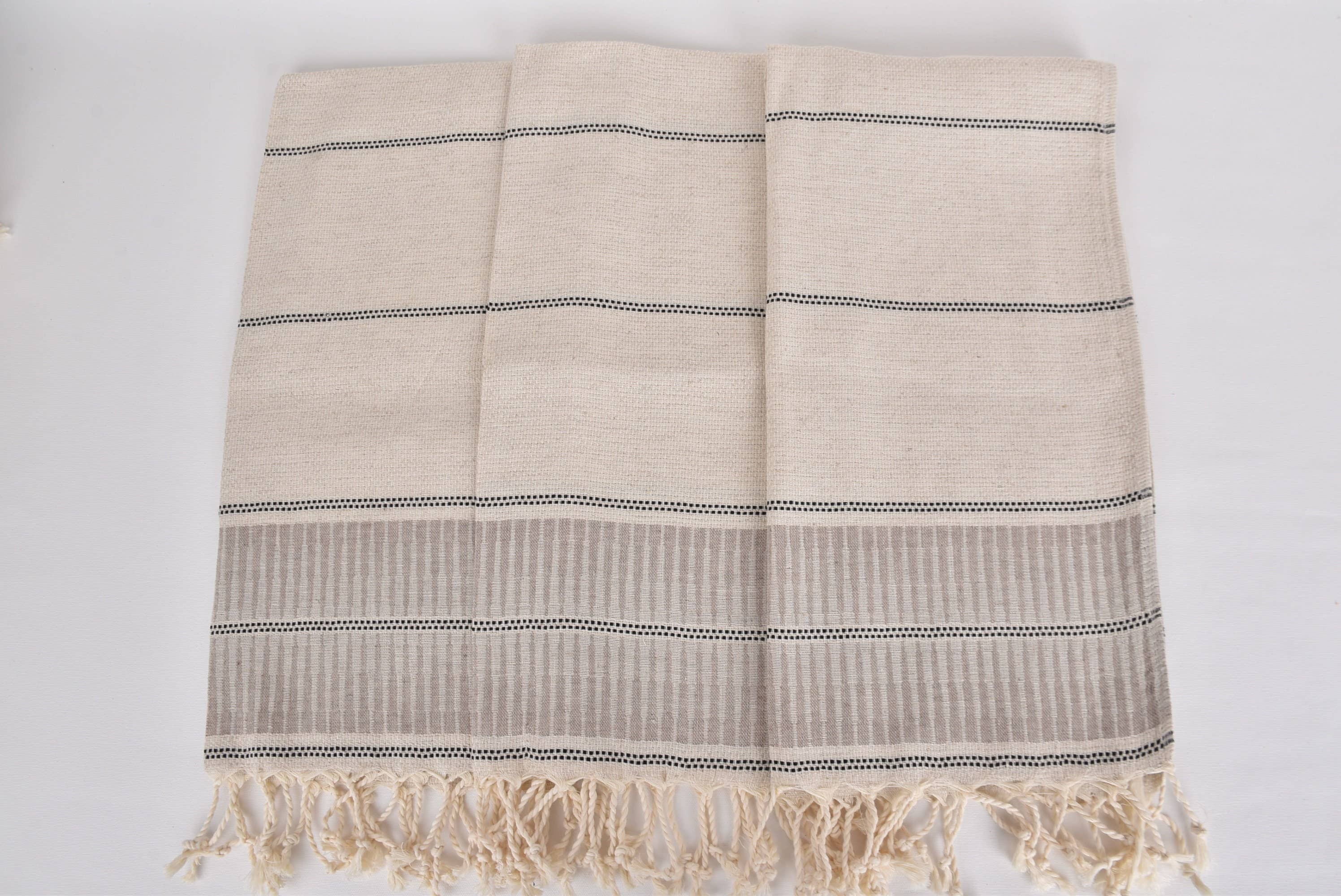 Beige towel with black stripes and fringes on a white background