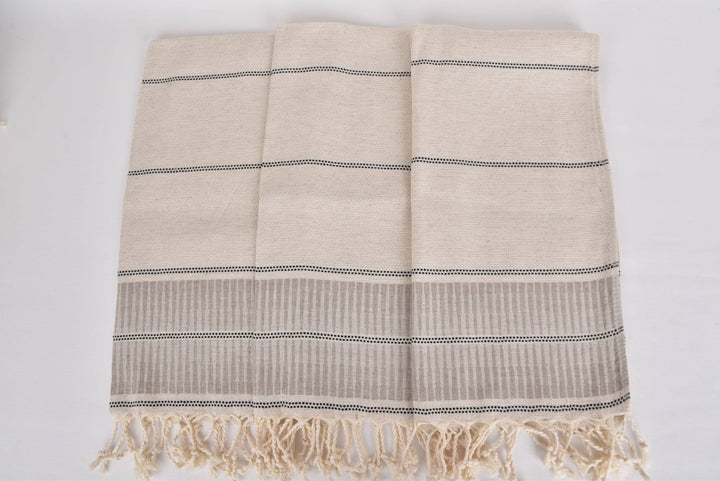 Beige towel with black stripes and fringes on a white background