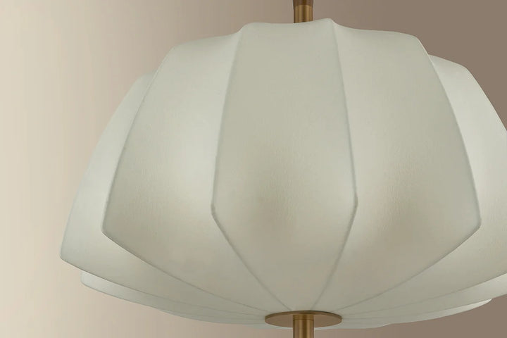 White lampshade with a gold fixture against a beige background