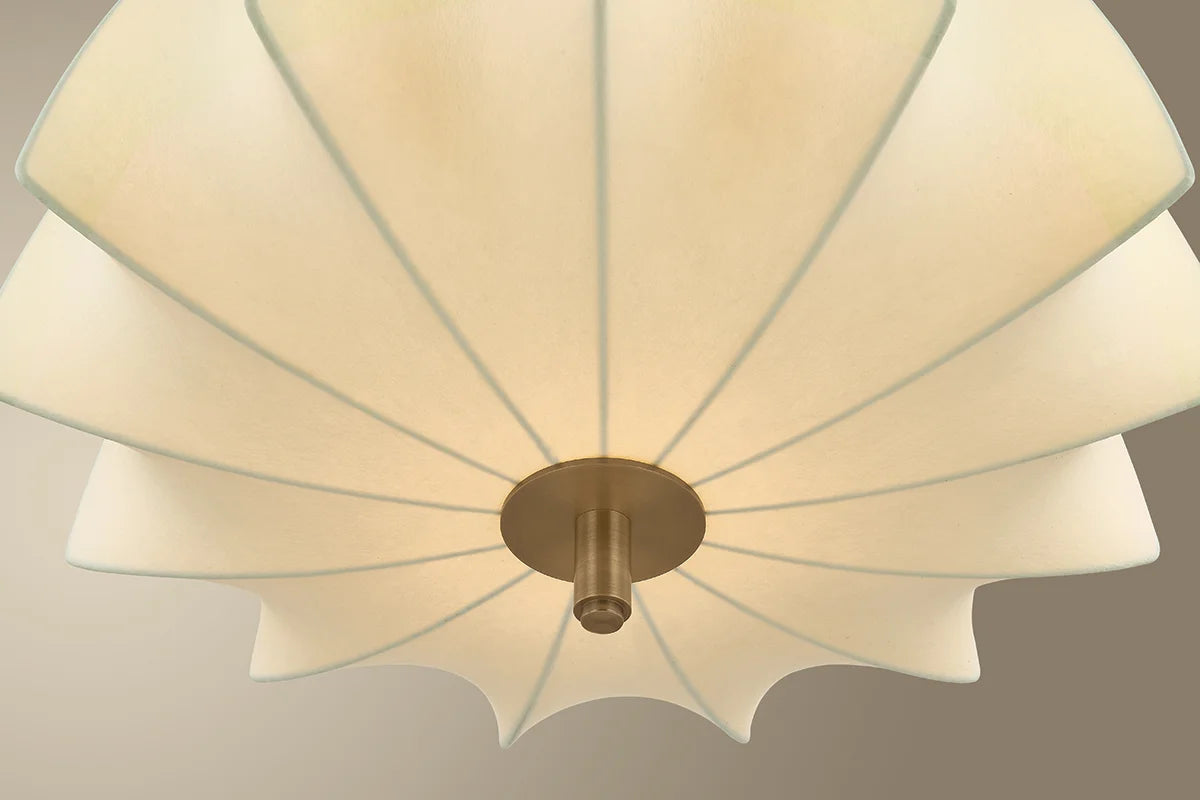 Ceiling light fixture with white lampshade and gold fixture on a neutral background