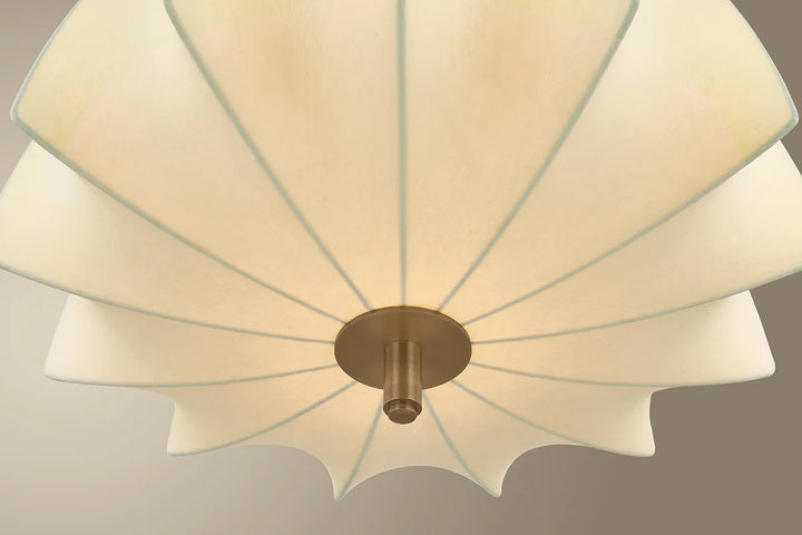 Ceiling light fixture with white lampshade and gold fixture on a neutral background