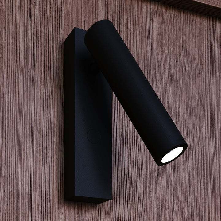 Black cylindrical wall light fixture on a wooden surface