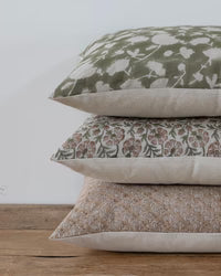 Stack of floral patterned pillows on a wooden surface with a white background