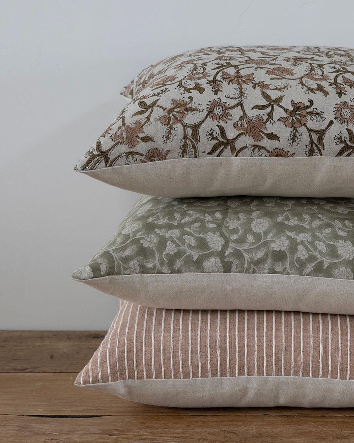Stack of three patterned pillows on a wooden surface with a white background