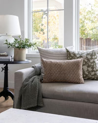 Cozy living room with a gray sofa, cushions, and a side table with a lamp.
