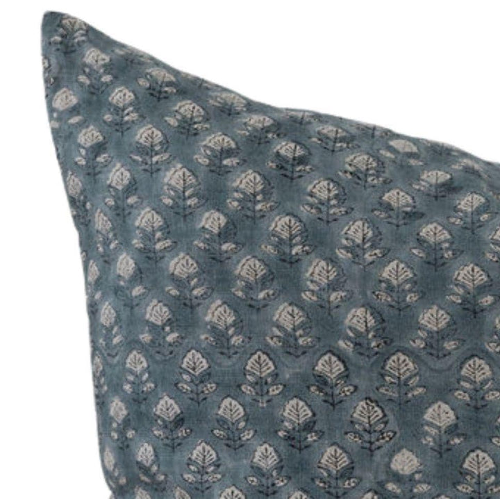Blue pillow with white floral pattern on a white background