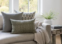 Cozy living room with a beige sofa, patterned cushions, and a wooden side table.