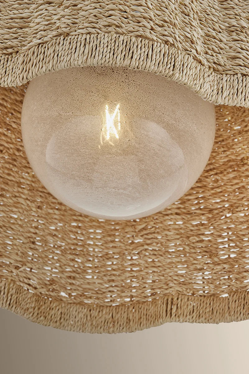 Close-up of a frosted bulb inside a woven pendant light shade with natural fiber detailing