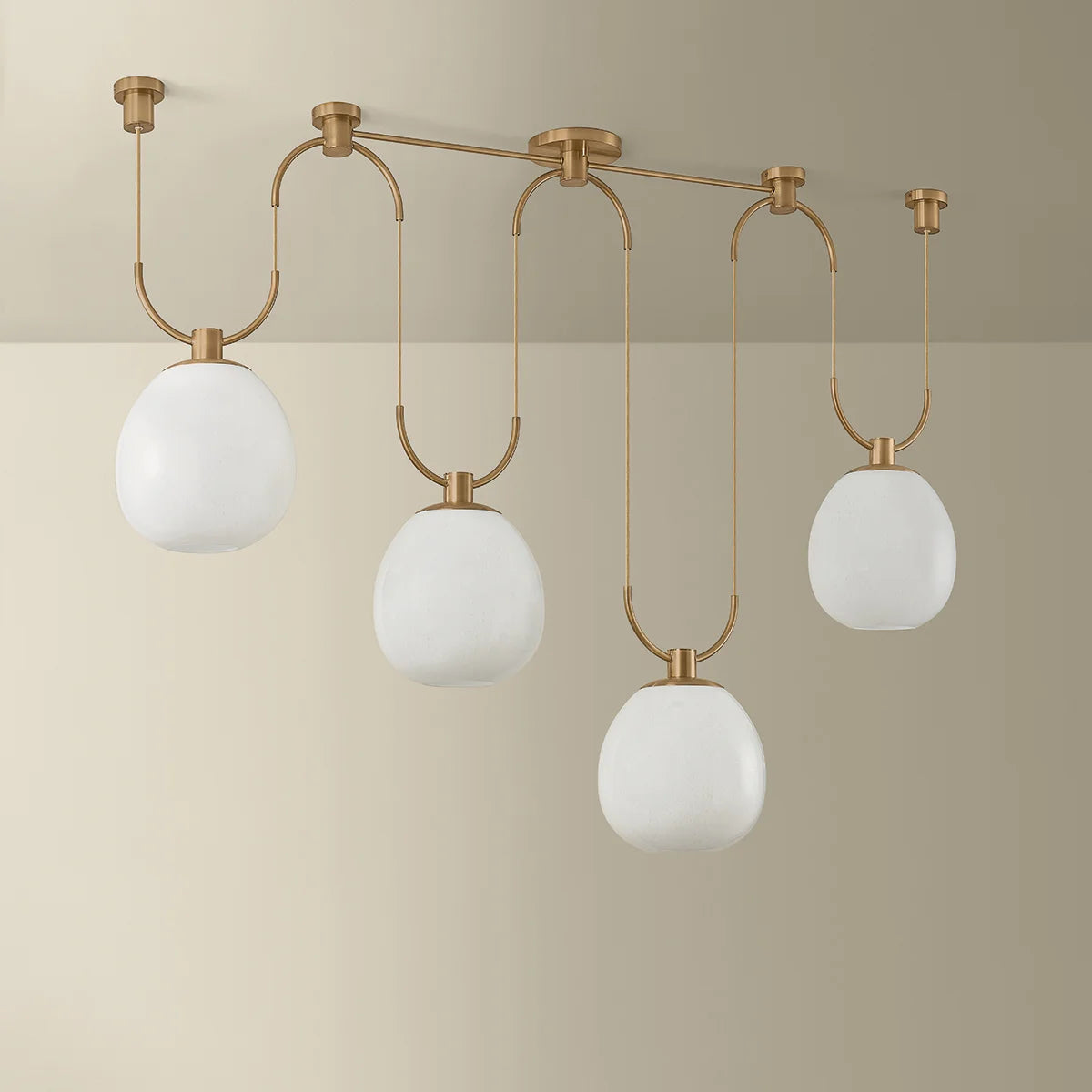 Modern ceiling light fixture with gold frame and white glass shades on a beige background